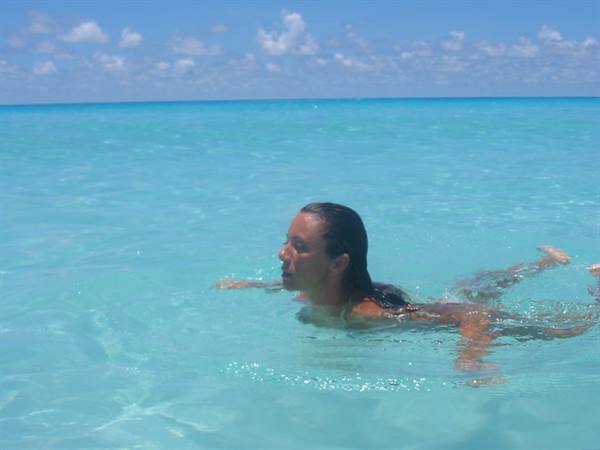 Woman with wet hair swimming in turquoise sea under blue sky