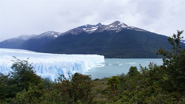Perito Moreno glacier, blue ice wall over turquoise lake beneath snowy peaks