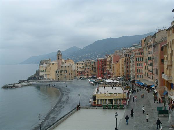 Bogliasco: colorful houses by the pebble beach, bell tower, cloudy sky, strolling people