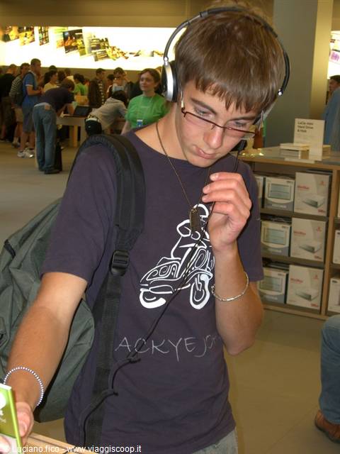 Teenager wearing headphones listens to music in a crowded Apple Store