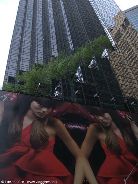Red-dress model billboards beneath the glass Trump Tower in New York