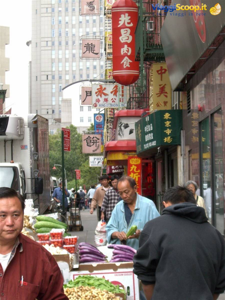 New York's Chinatown: vendor preparing vegetables among Chinese signs and skyscrapers