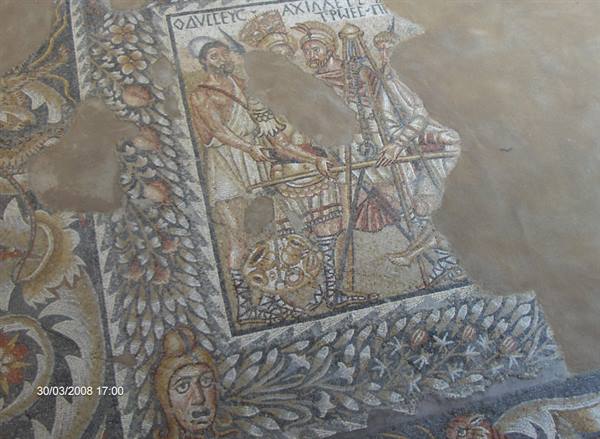 Ancient floor mosaic with robed figures and Greek inscription, colored tesserae