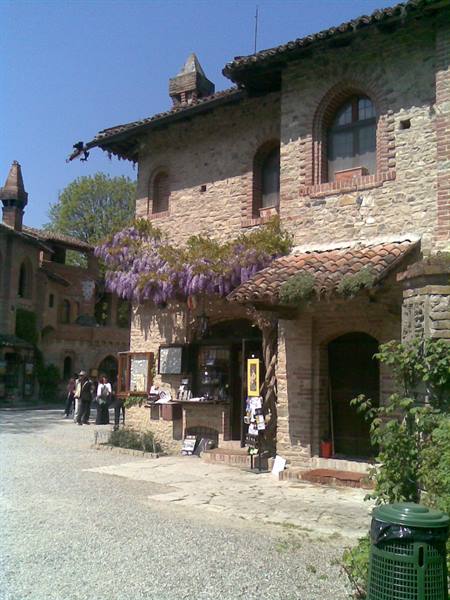 stone houses with tiled roofs and purple wisteria, visitors under blue sky