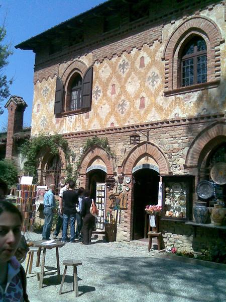 Tourists browsing craft shops on a decorated brick building, Grazzano Visconti