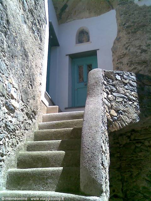 Stone staircase with plastered handrail leads up to turquoise door