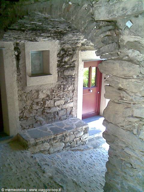 Stone arch with red door and small window in an old village