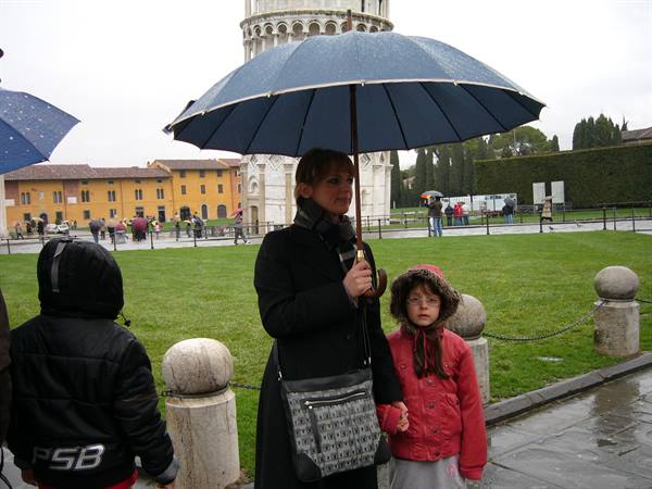 Mother with umbrella and child in front of Pisa Leaning Tower