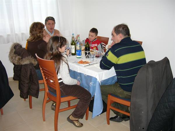 Family eating at a table with blue tablecloth, bottles and pasta plates