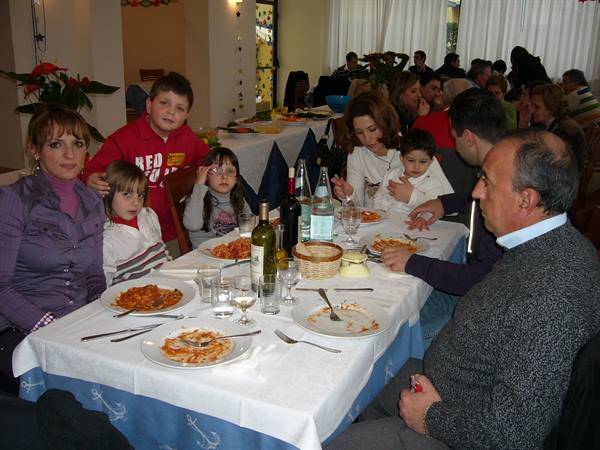 Family at a dining table, pasta plates and wine bottles