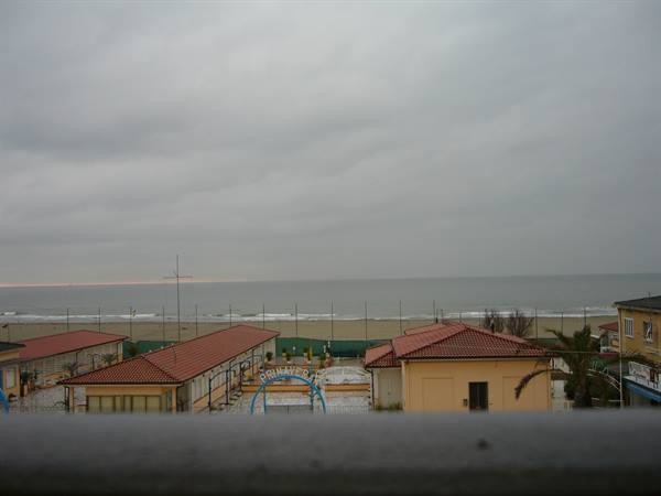 Viareggio: beach establishments with red roofs by the shore under cloudy skies