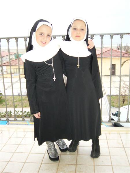 Children dressed as nuns with rosary on a balcony in Viareggio