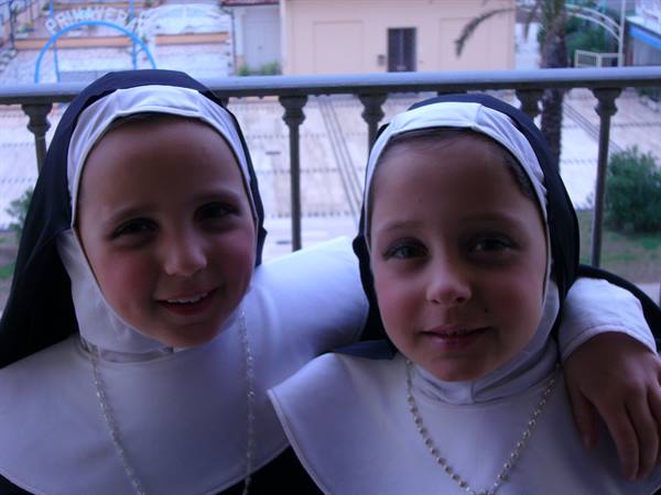 Children in nun costumes on a balcony, Viareggio's Principe sign behind