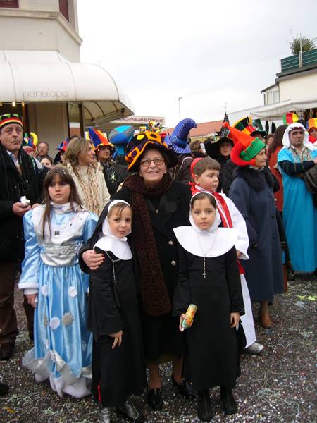 Children in costumes and a smiling elderly woman in the Viareggio carnival crowd