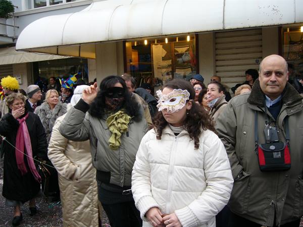 Crowd in carnival masks under Viareggio arcades, man wearing a camera