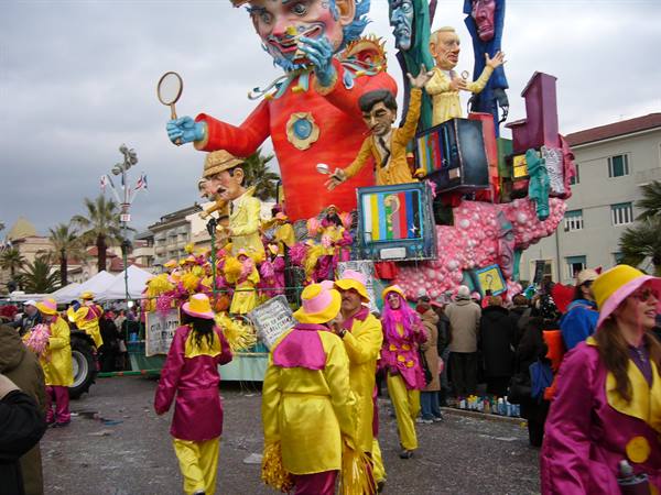 Viareggio Carnival: papier-mâché float and yellow-pink masked paraders marching