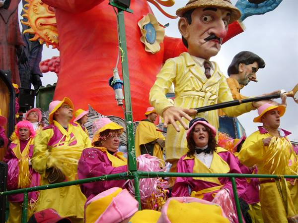 Viareggio Carnival: maskers in yellow and pink on a giant papier-mâché float