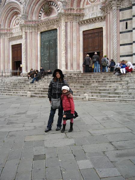Woman and child on the steps of Siena Cathedral, marble facade