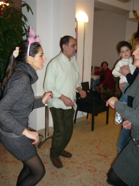 Guests dance indoors among scattered confetti, one woman wearing pink headband