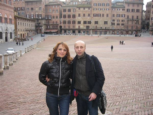 Couple in front of Piazza del Campo in Siena, herringbone bricks and medieval buildings