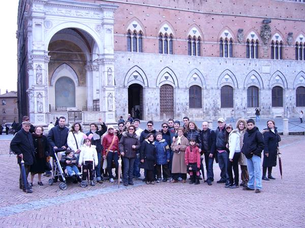 Tourist group posing in Siena's Piazza del Campo before the Palazzo Pubblico
