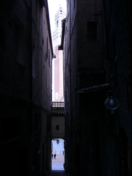 Dark brick alley, illuminated civic tower visible at the end