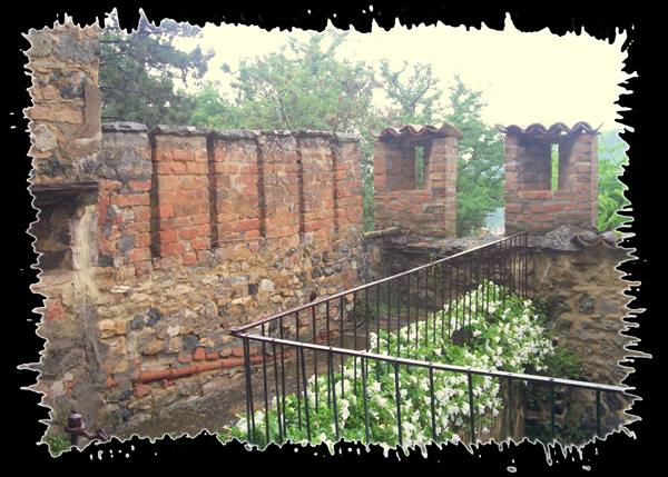 Brick and stone walls with battlements, iron railing and white flowers