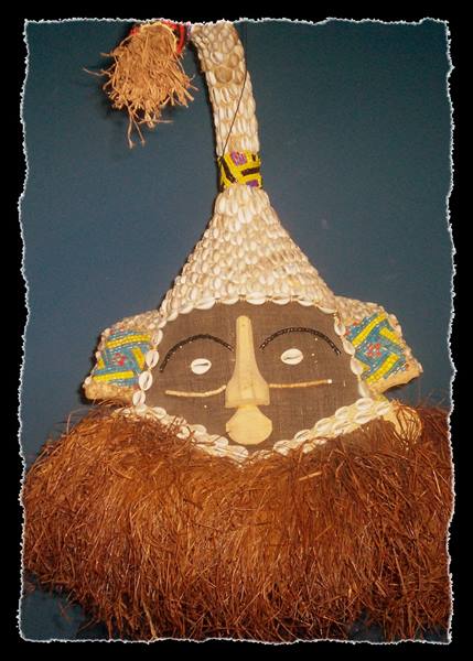 Tribal mask of shells, raffia and rope hanging on blue wall