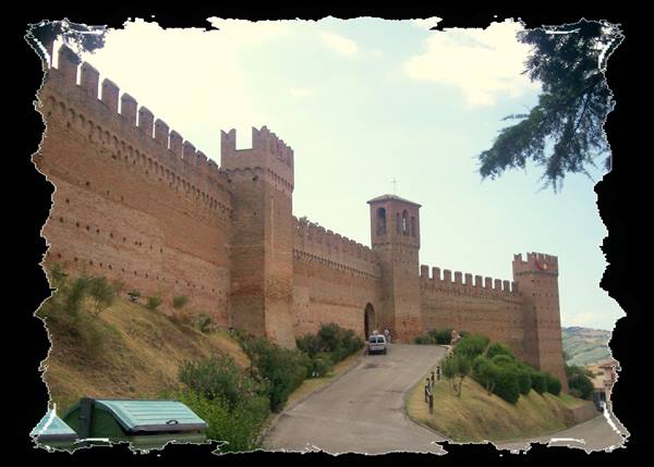 Gradara castle crenellated brick walls with tower and uphill road