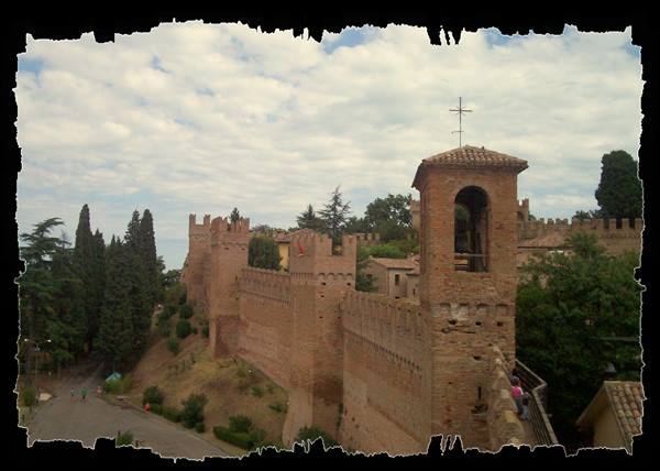 Crenellated brick walls with bell tower and visitors, Gradara