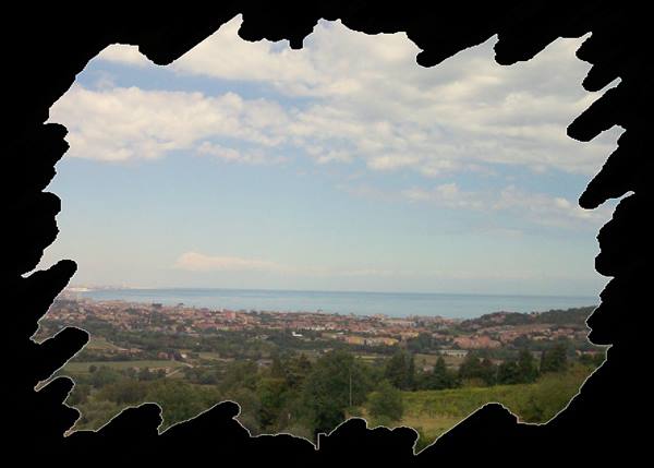 Town among green hills facing the Adriatic Sea, cloudy sky