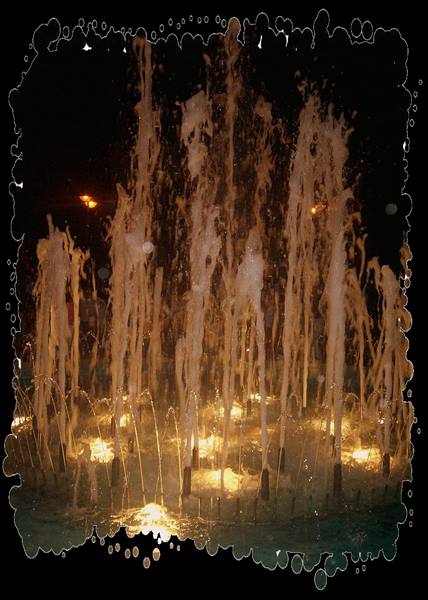 Water jets lit by amber lights in the night fountain