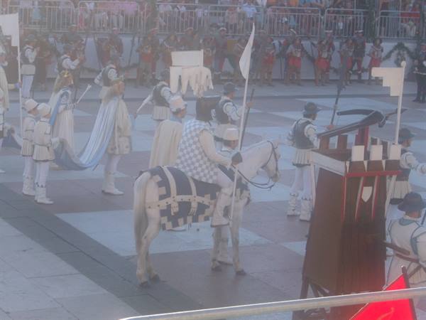 Knight on white horse parading in square during medieval historical procession