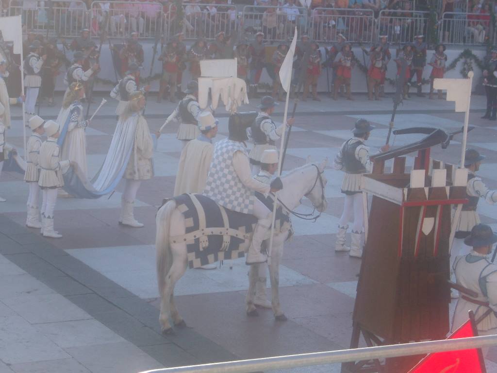 Knight on white horse parading in square during medieval historical procession