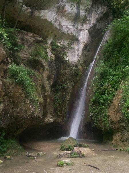 Waterfall sliding over mossy limestone rocks into a shallow green pool