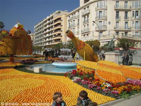 Citrus sculptures at Menton's Lemon Festival, with fountain and children nearby
