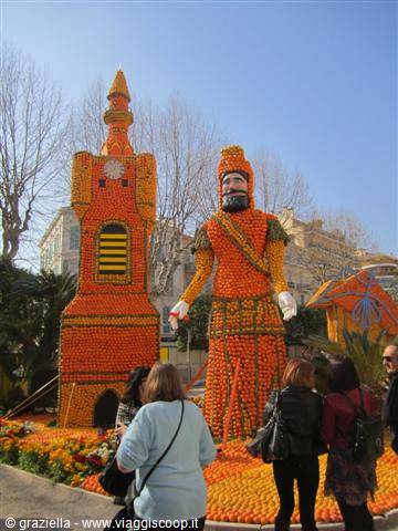 Citrus fruit sculptures in Menton: tower and mustached giant, visitors watching