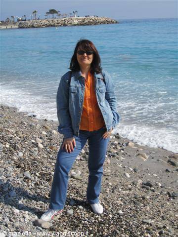 Woman in jeans and denim jacket posing on pebble beach by the sea