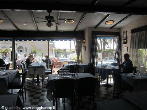 Restaurant dining room with set tables, beamed ceiling and windows overlooking the sea
