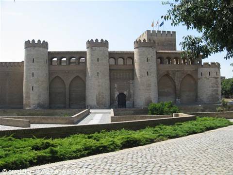 Aljafería Palace in Zaragoza, crenellated stone walls under sunlight