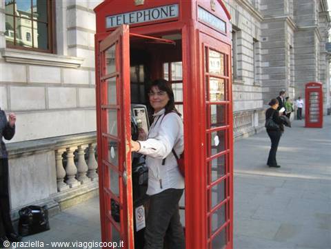 Smiling woman inside a classic red London telephone booth