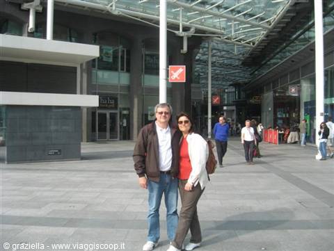 Smiling couple in modern glass and steel covered plaza, Liverpool One