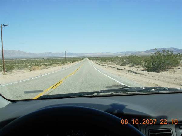 Straight Mojave Desert road seen from a car dashboard