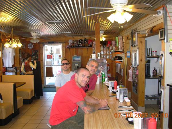 Three men at the wooden counter of a diner with corrugated metal ceiling