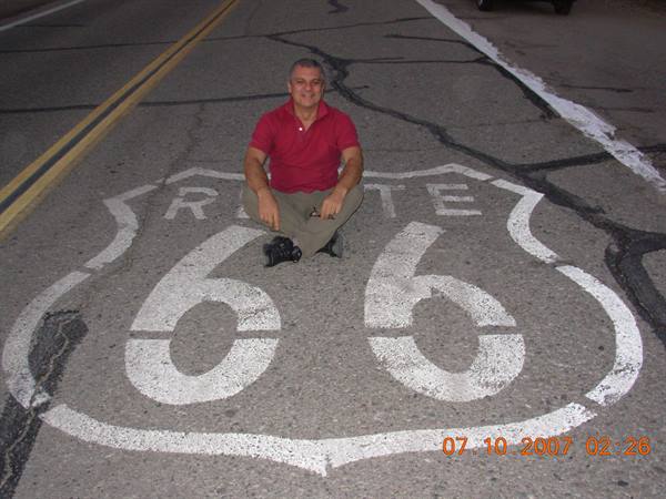 Man sitting on the Route 66 sign painted on the asphalt