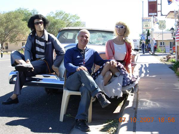 Tourist sitting between two mannequins on a vintage car along Route 66 in Seligman