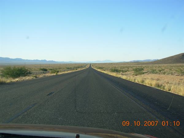 Straight asphalt highway crossing the desert with distant mountains ahead