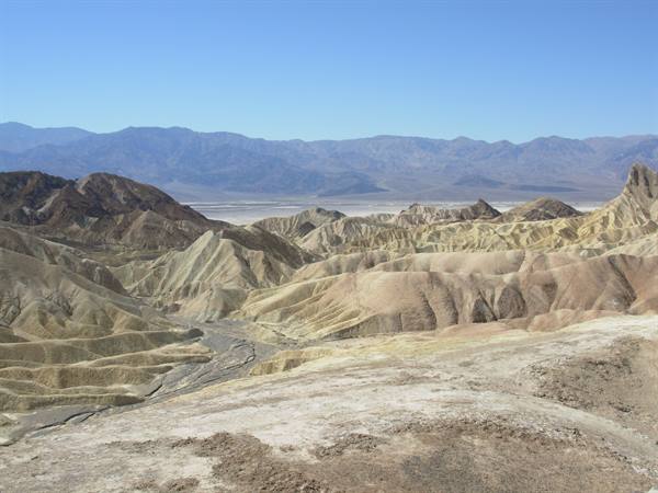 Zabriskie Point, Death Valley: eroded ochre and golden badlands hills under clear blue sky