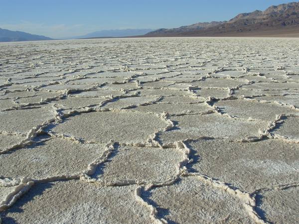 Salt crust polygons at Badwater Basin, Death Valley, mountains under blue sky