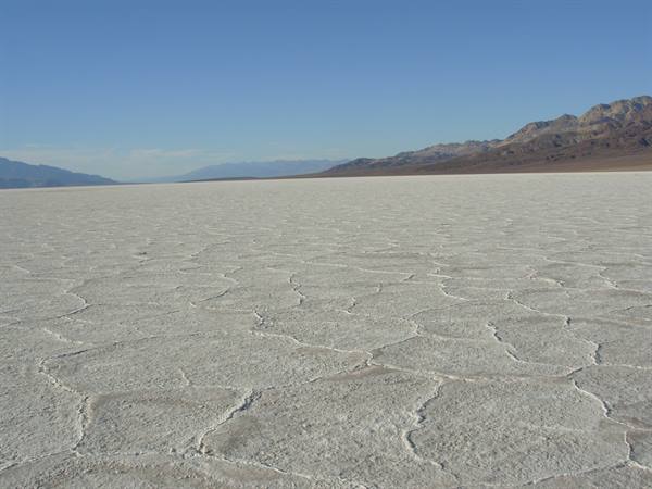 Salt polygons at Badwater Basin, dry mountains and clear blue sky